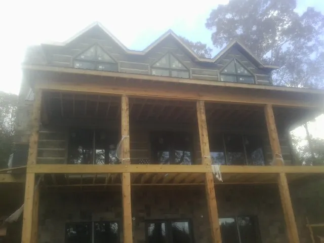 Dormers and porch framing on a large log home under construction — Roof Coating work by our crew in Superior