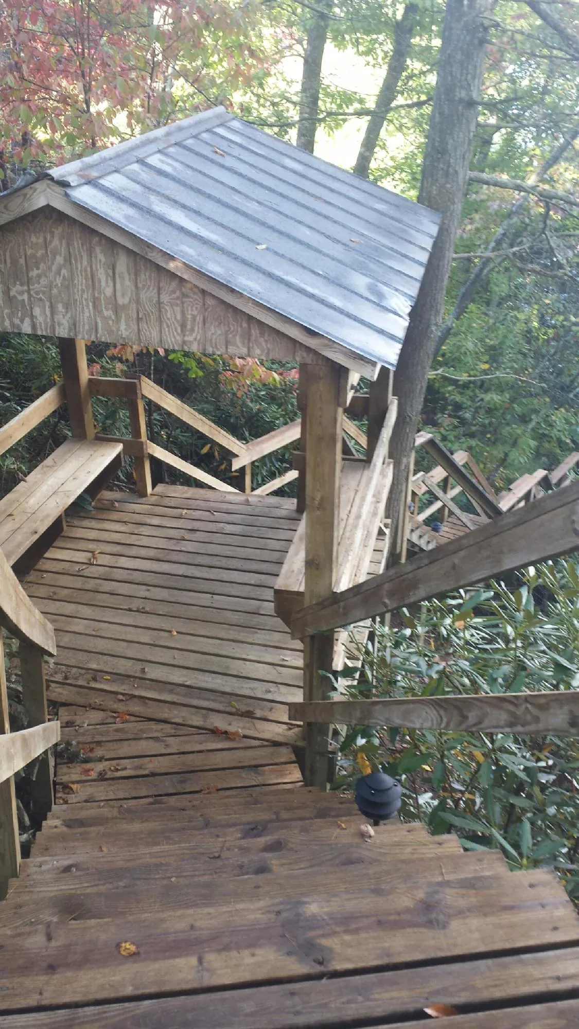 Metal roofed shelter over wooden steps on a wooded walkway — Skylight Repair & Installation work by our crew in Superior