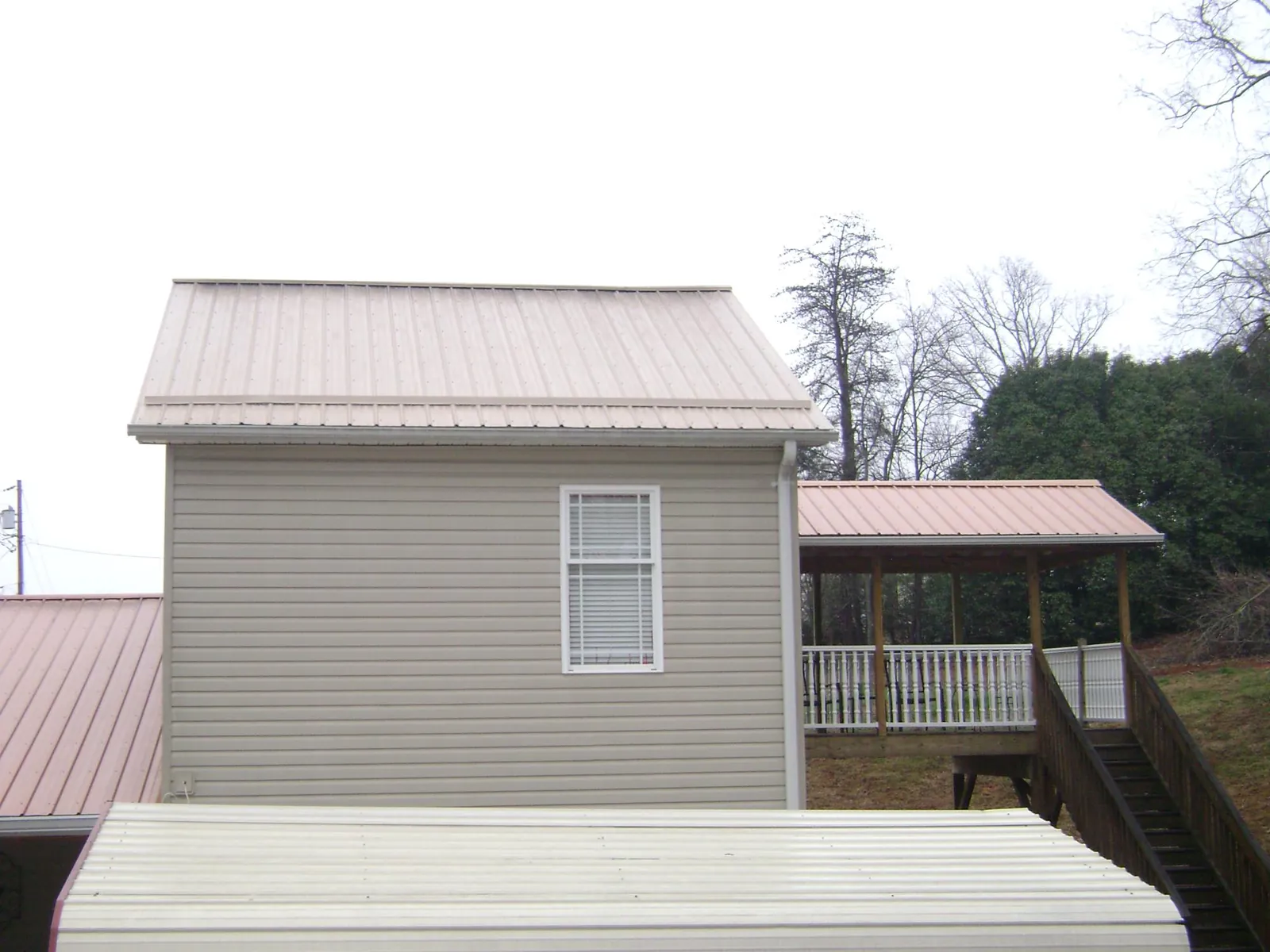 Tan metal roofs on a two story addition and attached porch, from a Roof Replacement job in Superior